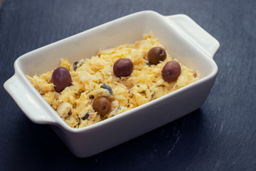 typical portuguese dish eggs with cod fish and olives in white dish Bacalhau a lisbonense