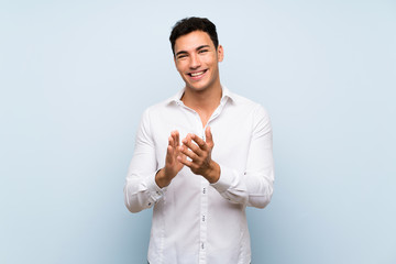 Handsome man over blue wall applauding after presentation in a conference