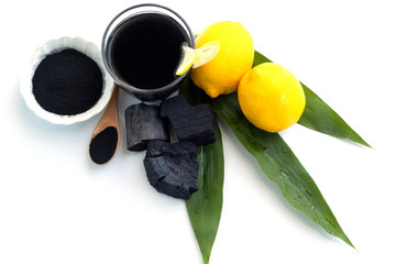 Detox activated charcoal black lemonade on white background, with leaves and lemon