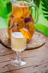 Glass of white sparkling wine sangria decorated with citrus slices and season fruits on wooden table.