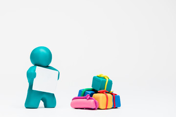 A man made from plasticine next to a big pile of gifts on white background , aligned to the left.