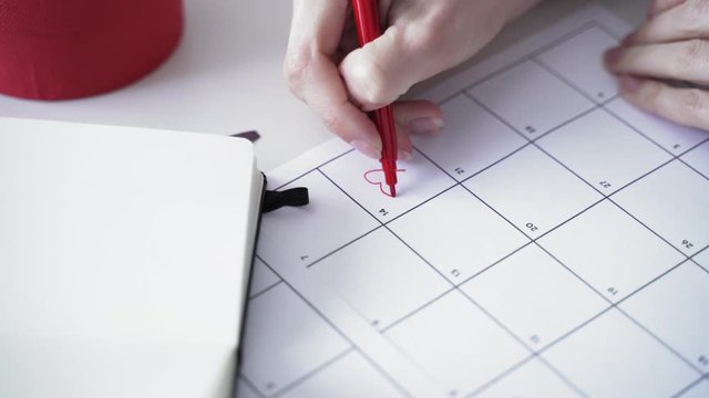 Woman fills data in graphs on paper. Records information. Woman is engaged in office work. Graphic charts,indicators. Woman works at the offside table. Woman draws symbols on the paper