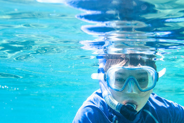 Mediterranean Sea.A boy snorkeling in a deep blue water, sun rays. 