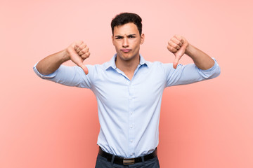 Fototapeta premium Handsome man over pink background showing thumb down