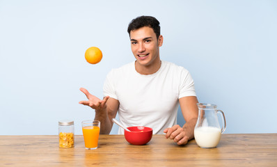 Handsome man in having breakfast and holding an orange