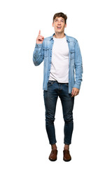 A full-length shot of a Handsome young man pointing up and surprised over isolated white background