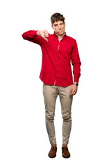 A full-length shot of a Handsome young man showing thumb down sign over isolated white background