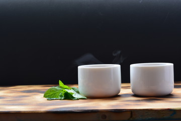 a cup of tea with mint leaves  in front of a black background