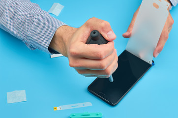 The man replacing the broken tempered glass screen protector for smartphone.