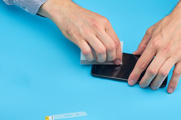 The man replacing the broken tempered glass screen protector for smartphone.