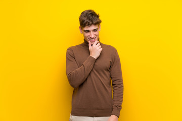 Handsome young man over isolated yellow background looking to the side