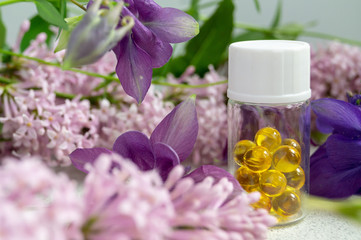 Fototapeta na wymiar a jar with fish oil capsules and purple liliac flowers