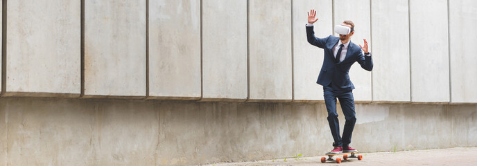 Panoramic view of businessman in formal wear and vr headset riding on skateboard