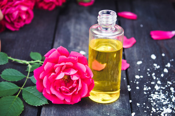 Rose essential oil closeup on a dark wooden background.