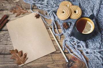 Autumn still life with cup of tea, cookies, sweater and leaves on wooden background. concept of cozy autumn, fall season Form for text.