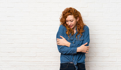 Redhead woman over white brick wall freezing