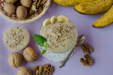 .Banana ice-cream dessert in a glass bowl with walnuts on a purple background with mint