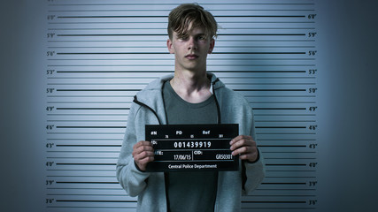 In a Police Station Arrested Drug Addict Teenage Posing for a Front View Mugshot. He is Heavily...