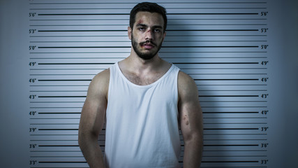 In a Police Station Arrested Beaten Man Poses for Front View Mugshot. He Wears Singlet, is Heavily...