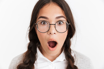 Portrait closeup of astonished teenage girl wearing eyeglasses and school uniform wondering with...