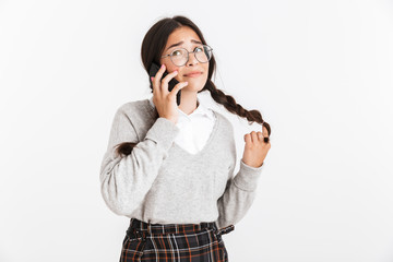 Photo closeup of pretty teenage girl wearing eyeglasses and school uniform rejoicing while talking on smartphone