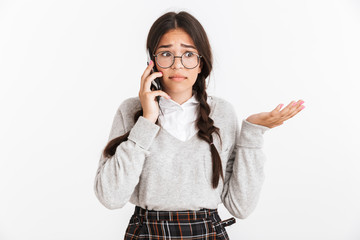 Photo closeup of sad puzzled teenage girl wearing eyeglasses and school uniform expressing confusion while talking on smartphone