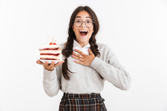Photo closeup of delighted teenage girl wearing eyeglasses smiling while holding big slice of birthday cake