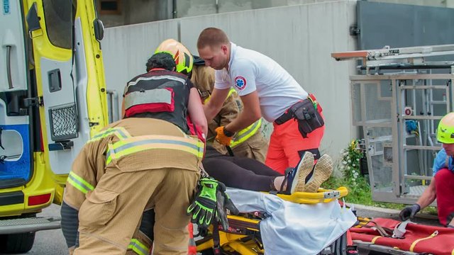 A team of firefighters and medical staff is helping an injured person and they have to bring her into the hospital as soon as possible.