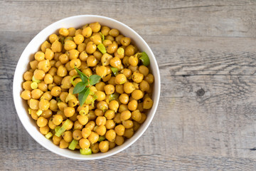 Cooked chickpeas with leek, chia seeds, sesame seeds and basil on top in white bowl. Flat lay, top view with copy space.