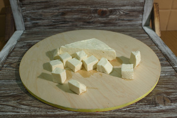 Stracchino cheese on a light wooden tray on a wooden background