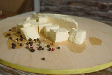 Stracchino cheese on a light wooden tray on a wooden background