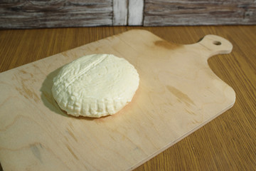 Fresh Adyghe cheese on a wooden tray on a wooden background