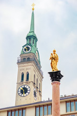 Obraz premium The Marian column (Mariensäule) and the steeple St. Peter's Church located on the Marienplatz in Munich. Bavaria, Germany