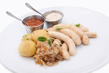  homemade sausages with boiled baby potatoes and fried cabbage. served with sauces. German, Russian, Ukrainian cuisine