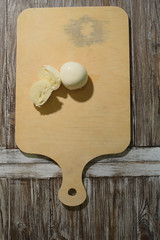 Fresh mozzarella cheese on a wooden tray on a wooden background