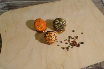 Orange, brown and black chevre cheese with spices on a wooden tray and wooden background