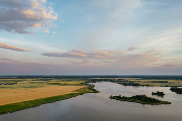 Fototapeta premium Sunset over the lake in western Poland, view of agricultural fields and water.