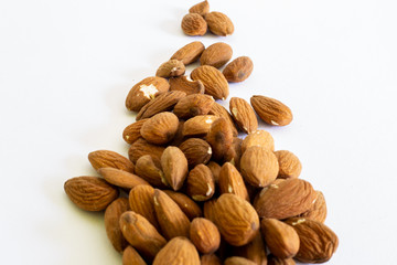 Brown dry almond seeds in small pile on a white background – Natural and organic nut used in cosmetics or food industry with copy space