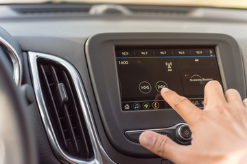 Obraz premium Male hand changing the radio station on car LCD infotainment screen