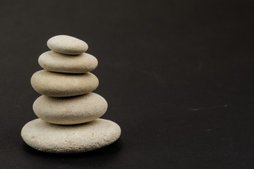 Fototapeta na wymiar stack of zen stones on the left side dark background