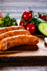 Raw sausages and vegetables on cutting board