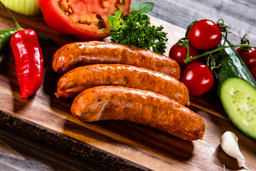 Raw sausages and vegetables on cutting board
