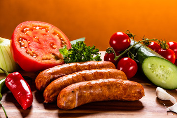 Raw sausages and vegetables on cutting board