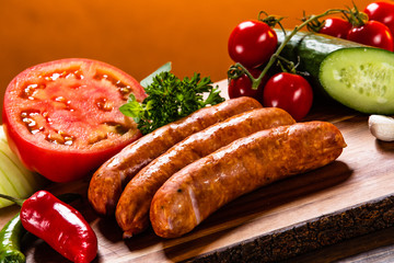 Raw sausages and vegetables on cutting board