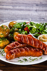 Grilled sausages, baked potatoes and vegetables
