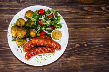 Grilled sausages, baked potatoes and vegetables