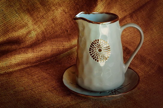 A set of ceramic dishes. Blue shiny jug and plate on natural fabric. Pottery craftsmanship. Rustic style