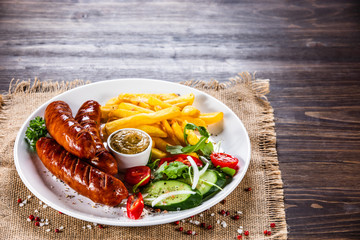 Grilled sausages, French fries and vegetables