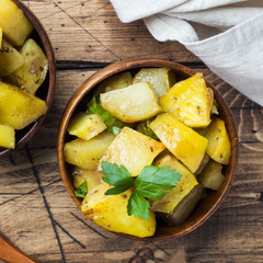 Baked potatoes with spices and herbs in wooden plate.