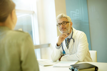 Mature doctor talking to patient in modern clinic